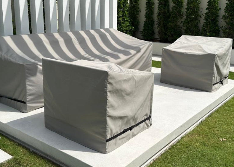 Outdoor furniture set with protective grey covers on a patio