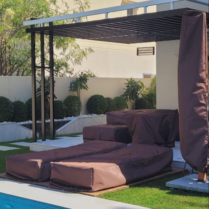 Covered outdoor seating area with pergola and lounge chairs in a garden setting.